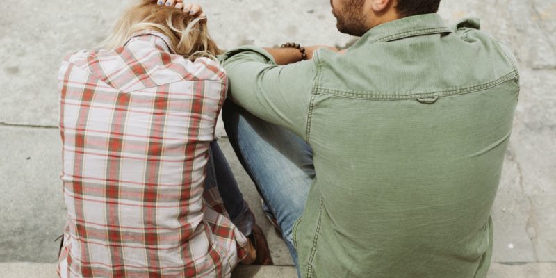 man-and-woman-sitting-on-sidewalk-226166